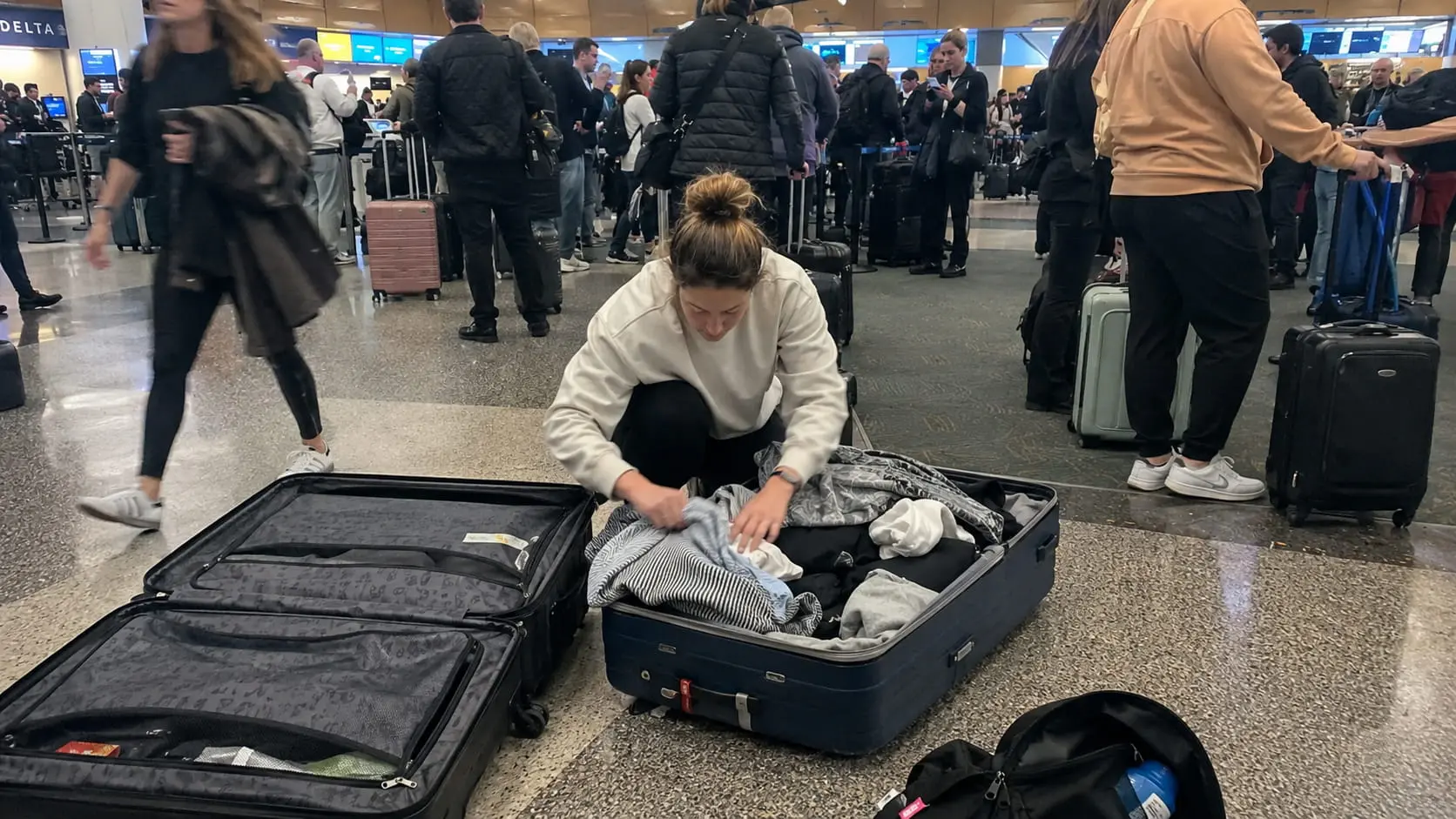 Woman reorganizing luggage at airport to avoid overweight fee