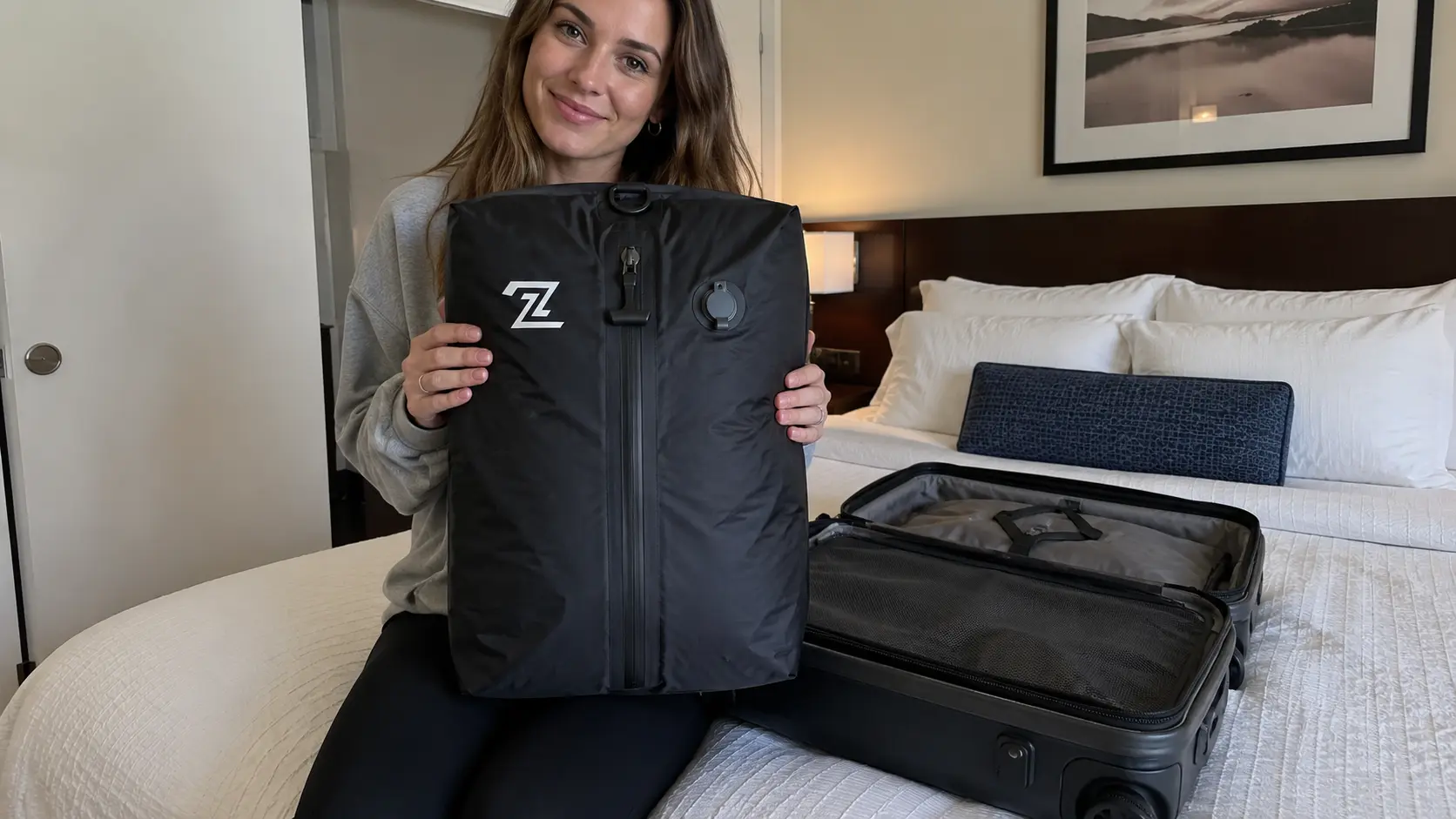 Amanda holding 2PackBag in hotel room next to carry-on suitcase